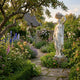 Woman Carrying Fruit Basket Marble Sculpture 180cm by Giant Sculptures, shown on a stone plinth in a cottage garden path beside foxgloves, roses, and an apple tree.