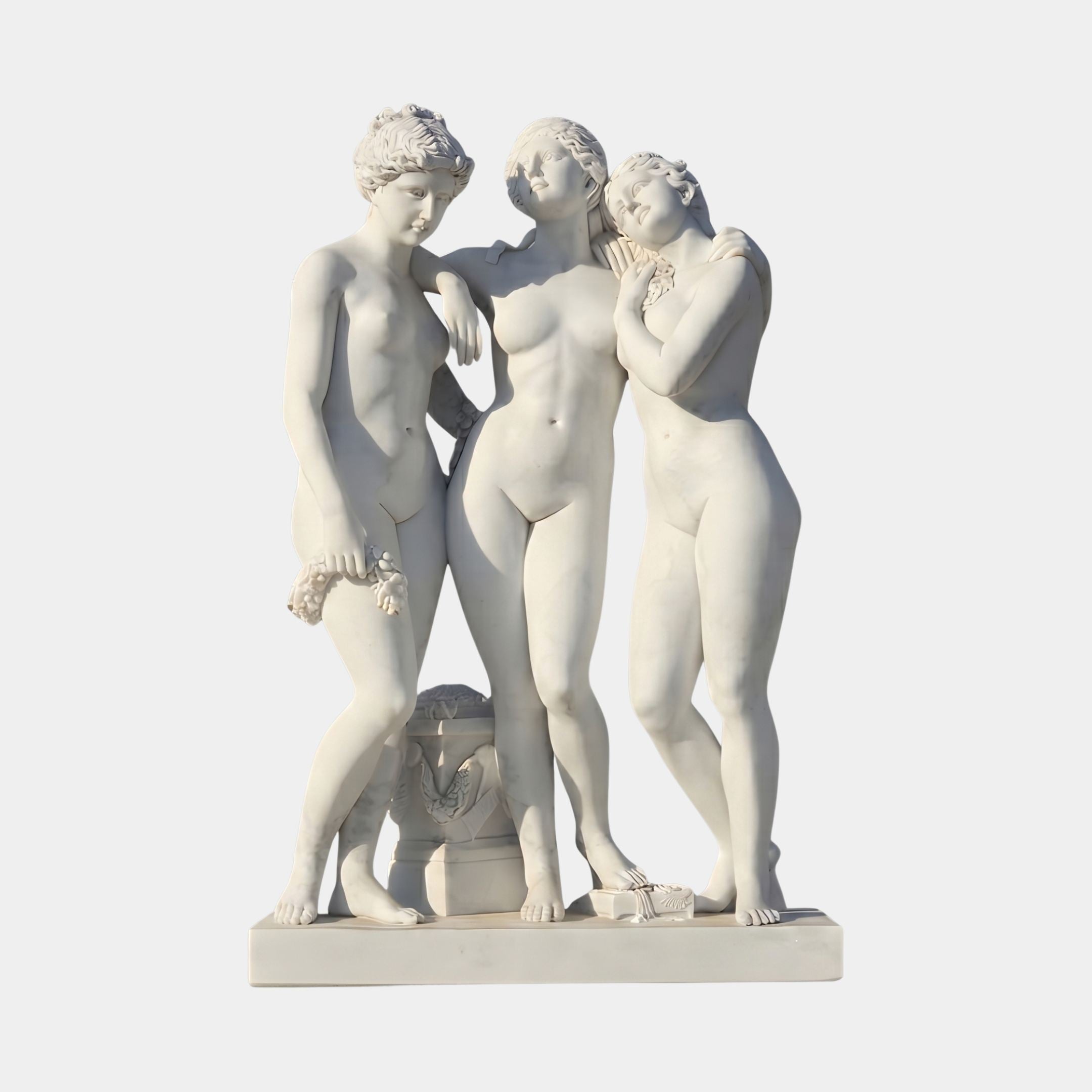 The Three Graces Marble Sculpture 100cm by Giant Sculptures, three nude female figures embracing beside a carved plinth, shown front-on against a plain background.