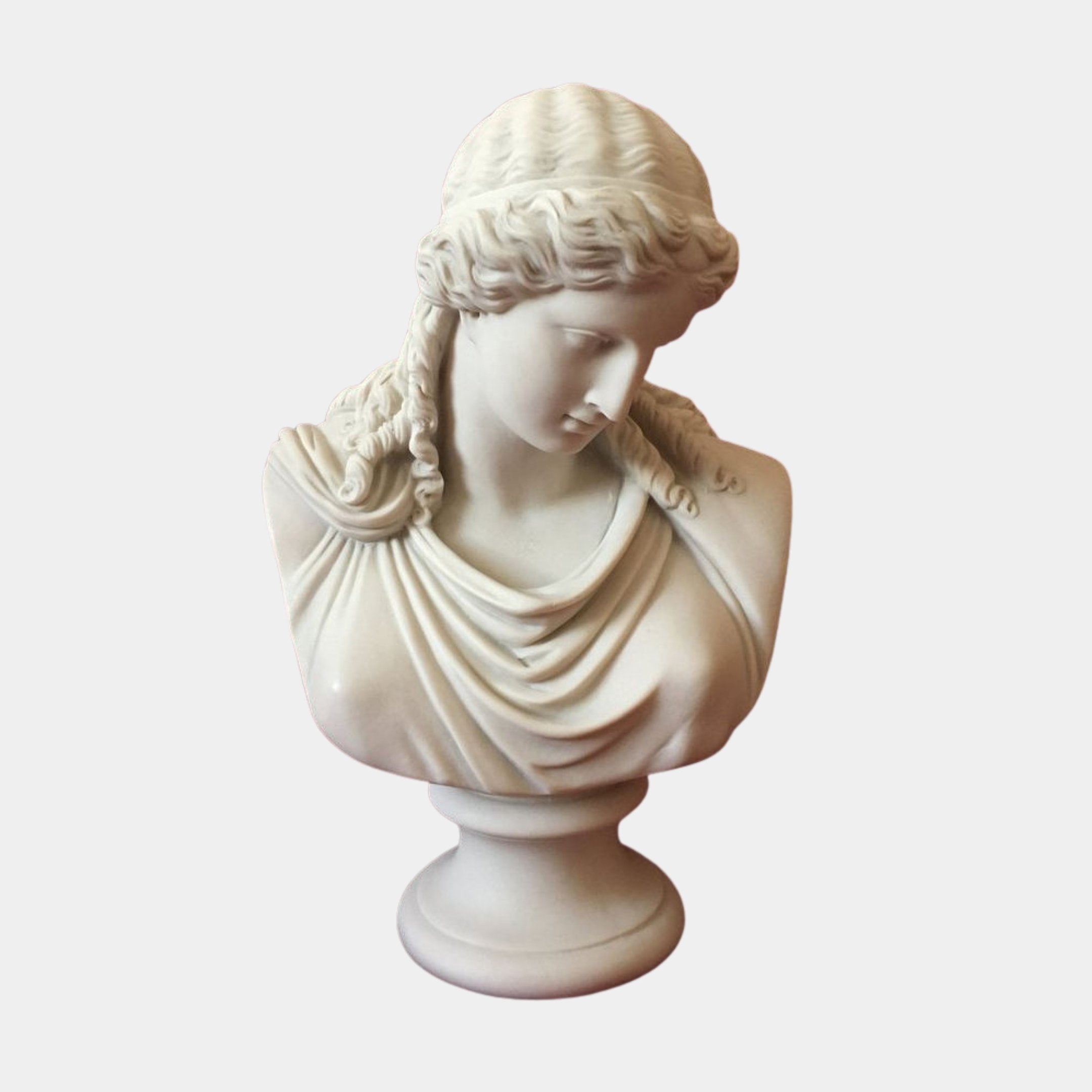 The Classical Beauty Marble Bust Sculpture - 65cm by Giant Sculptures features a woman with wavy hair and draped clothing, gazing downward. This elegant piece is crafted in marble and displayed against a plain, light background.