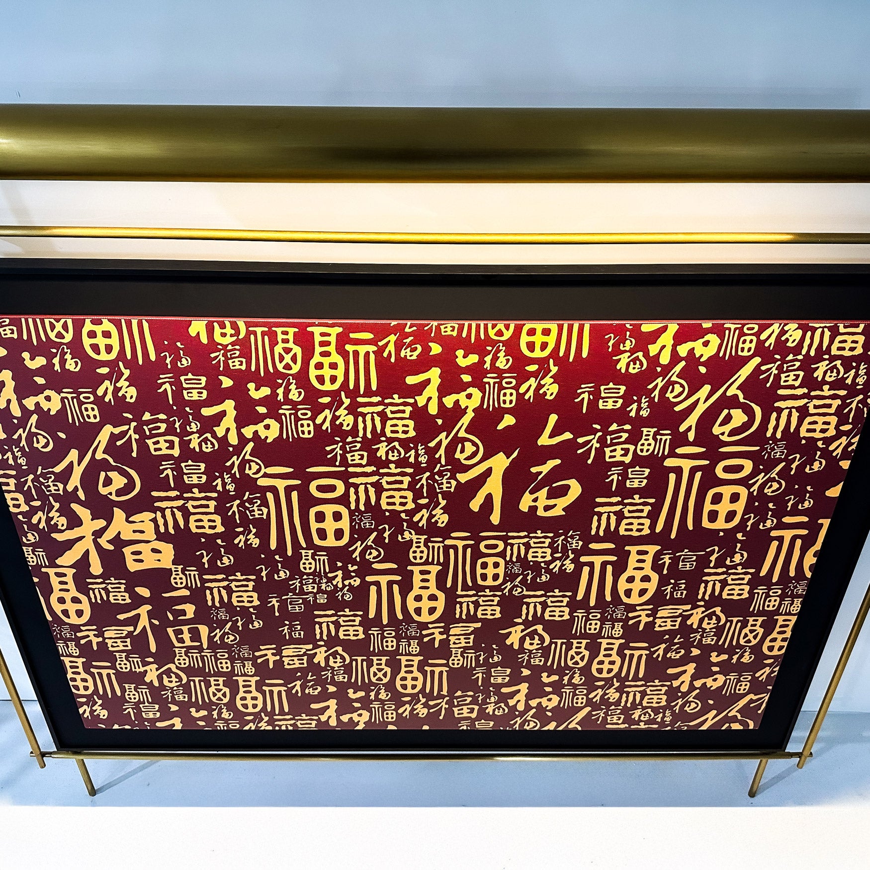 The Celestique Prosperity Script Framed LED Wall Art by Giant Sculptures showcases gold Chinese calligraphy on a vivid red background, symbolizing prosperity. A glossy gold metallic frame enhances the intricate design, adding elegance to this captivating piece.