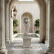 The Leafy Embrace Angel Marble Outdoor Sculpture by Giant Sculptures stands on a pedestal in a classical courtyard with ornate columns, mosaic-tiled floor, arched entryways, trimmed trees, and a rectangular reflecting pool in the background.