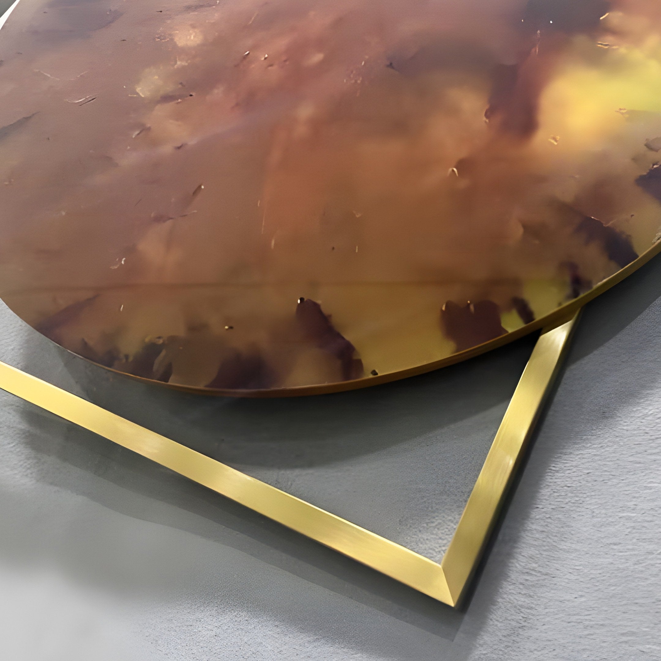 Close-up of the Aurenza Amber Acrylic & Metal Frame 3D Wall Art showing the amber acrylic disc with burnt sienna and ochre marbling resting on a gold-tone square frame.