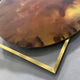 Close-up of the Aurenza Amber Acrylic & Metal Frame 3D Wall Art showing the amber acrylic disc with burnt sienna and ochre marbling resting on a gold-tone square frame.