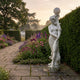Giant Sculptures' 210cm Female Figure Lamp Marble Sculpture on a stone path beside a flowering border of foxgloves and lavender at dusk.