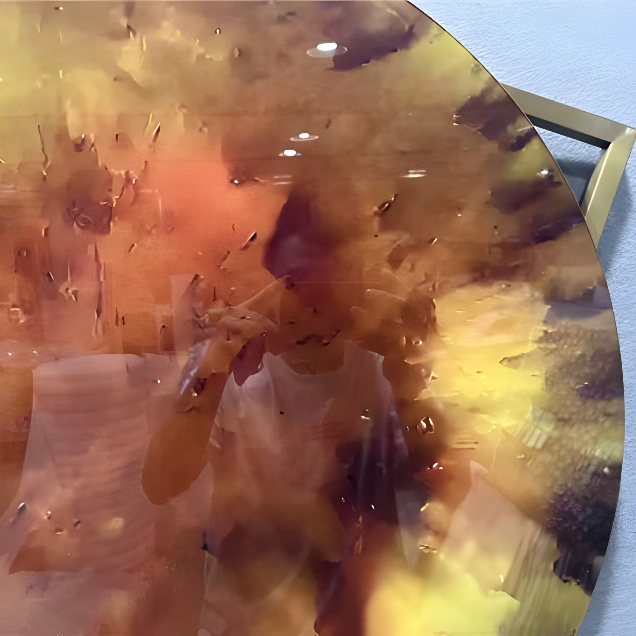 Close-up of the Aurenza Amber Acrylic & Metal Frame 3D Wall Art showing the glowing amber acrylic disc with burnt sienna to ochre marbling and gold-tone square frame mounted on a light wall.