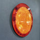 Galaxia Sun Crystal Porcelain LED Wall Art by Giant Sculptures shown at an angle on a grey wall, featuring a glowing amber and orange circular disc with solar flare-like marbling and a warm LED backglow.