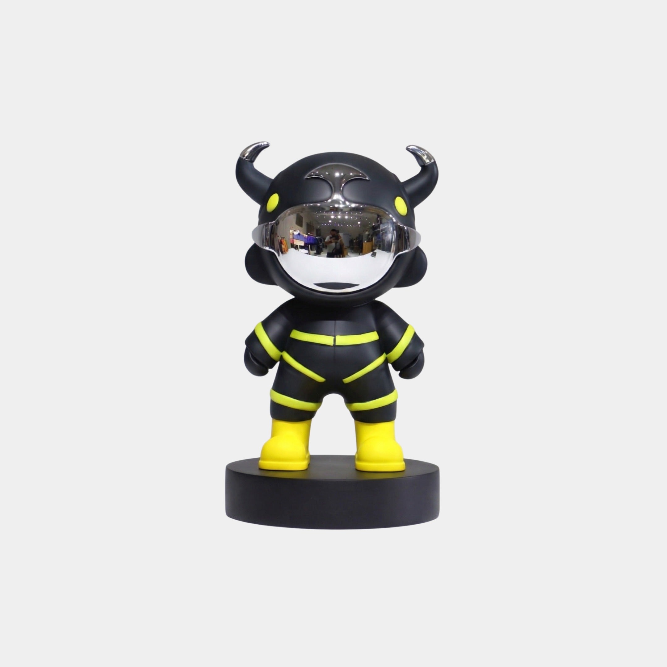 The Giant Sculptures Black Utility Astro Devil Figure - 15cm features a black body with yellow accents, a reflective silver horned helmet, yellow boots, and stands on a round black base against a plain white background.