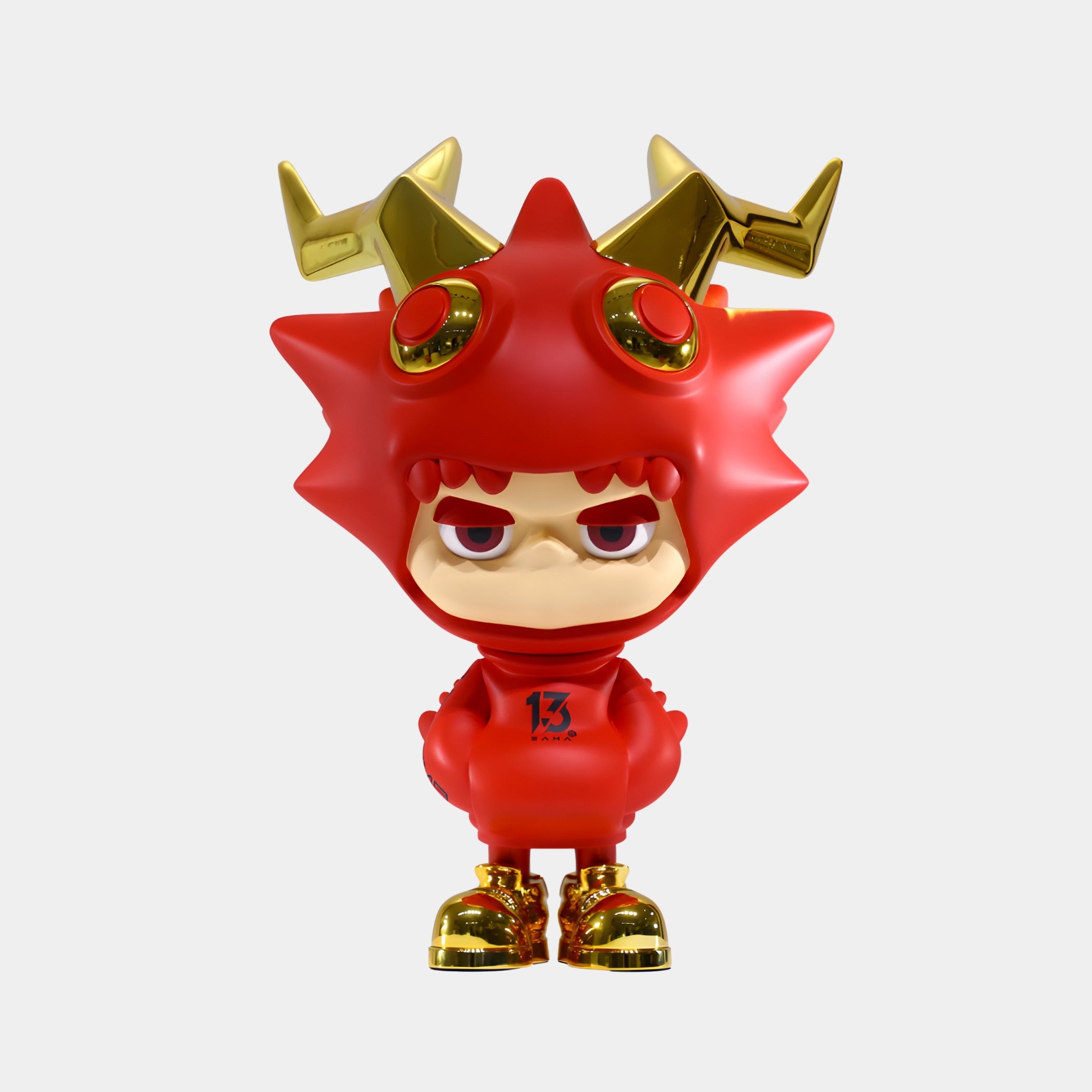The Giant Sculptures Red & Gold Horned Drakoz Sculpture (60cm) features a grumpy expression, red spiky suit, electroplated gold horns and shoes, number 13 on its chest, and red eyes. A plain white backdrop highlights its eye-catching design.