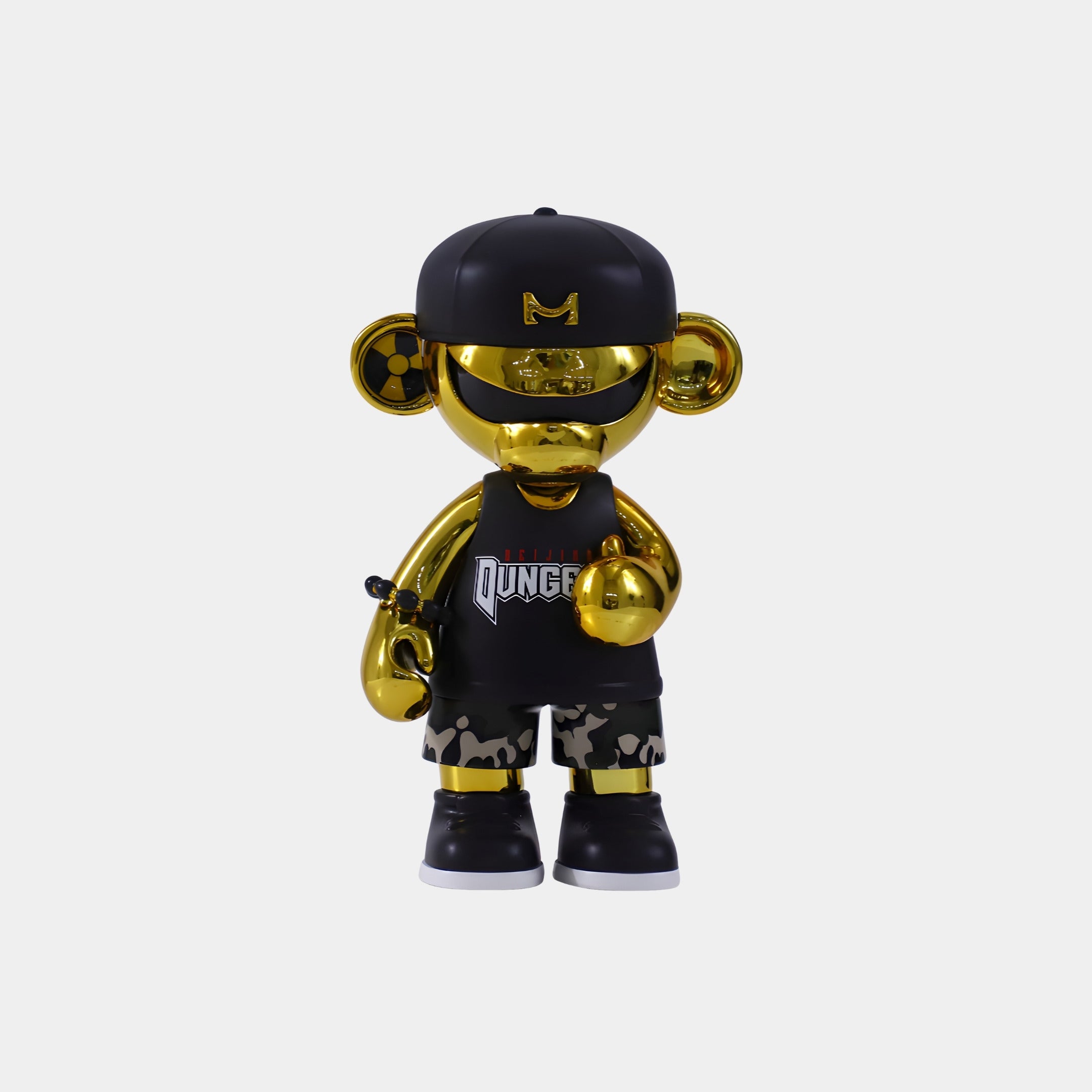 The Gold & Black Urbanix Monkey Figure (20cm) by Giant Sculptures features a shiny gold finish, black cap and sunglasses, Dungeon tank top, camo shorts, and black sneakers, all set against a plain white background.