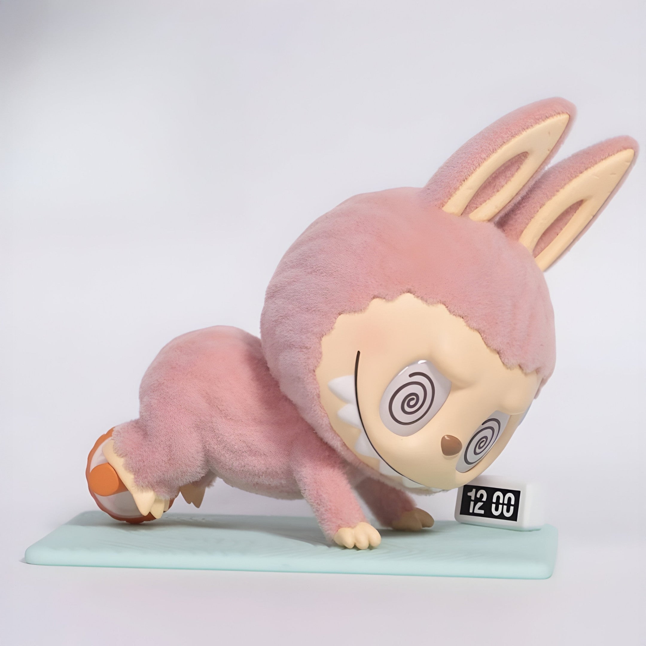 The Giant Sculptures Lazy Yoga Ab Roller Labubu Sculpture (100cm) features a pink bunny with a big head, spiral eyes, and a wide grin doing a push-up over a small digital clock on a light blue mat, mimicking an ab roller workout.