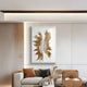 A modern living room with a beige sofa, brown and beige cushions, a brown ottoman, and the Lirien Twin Pearl Fronds Gold Sculptural 3D Wall Art by Giant Sculptures above the sofa. Neutral tones and minimal decor create a cozy, elegant feel.