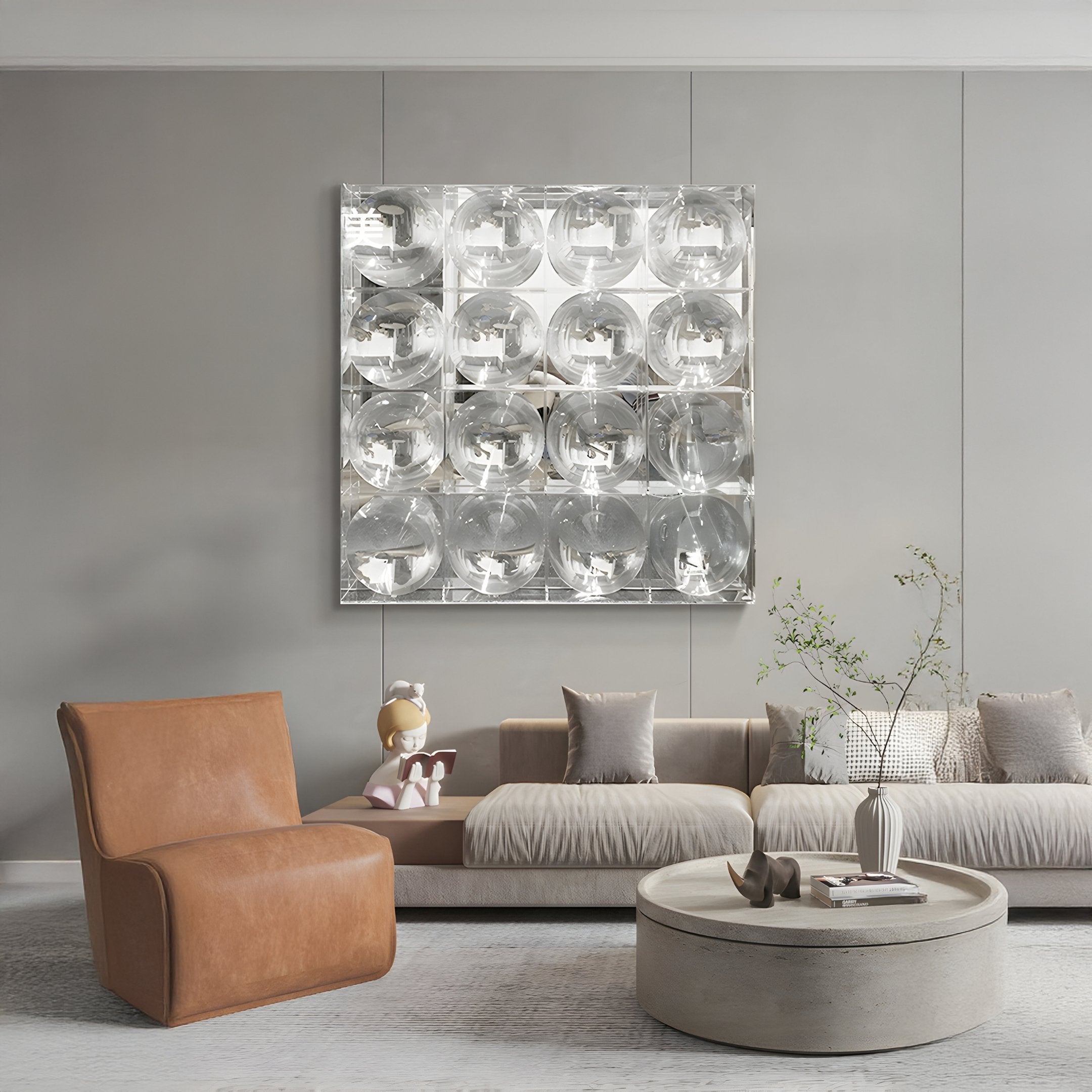 A modern living room featuring a tan leather chair, beige sofa, round coffee table, decorative plant, and Giant Sculptures’ Haloid II Bubble Grid Acrylic 3D Wall Art with shiny silver panels. A child-reading sculpture rests on the sofa.