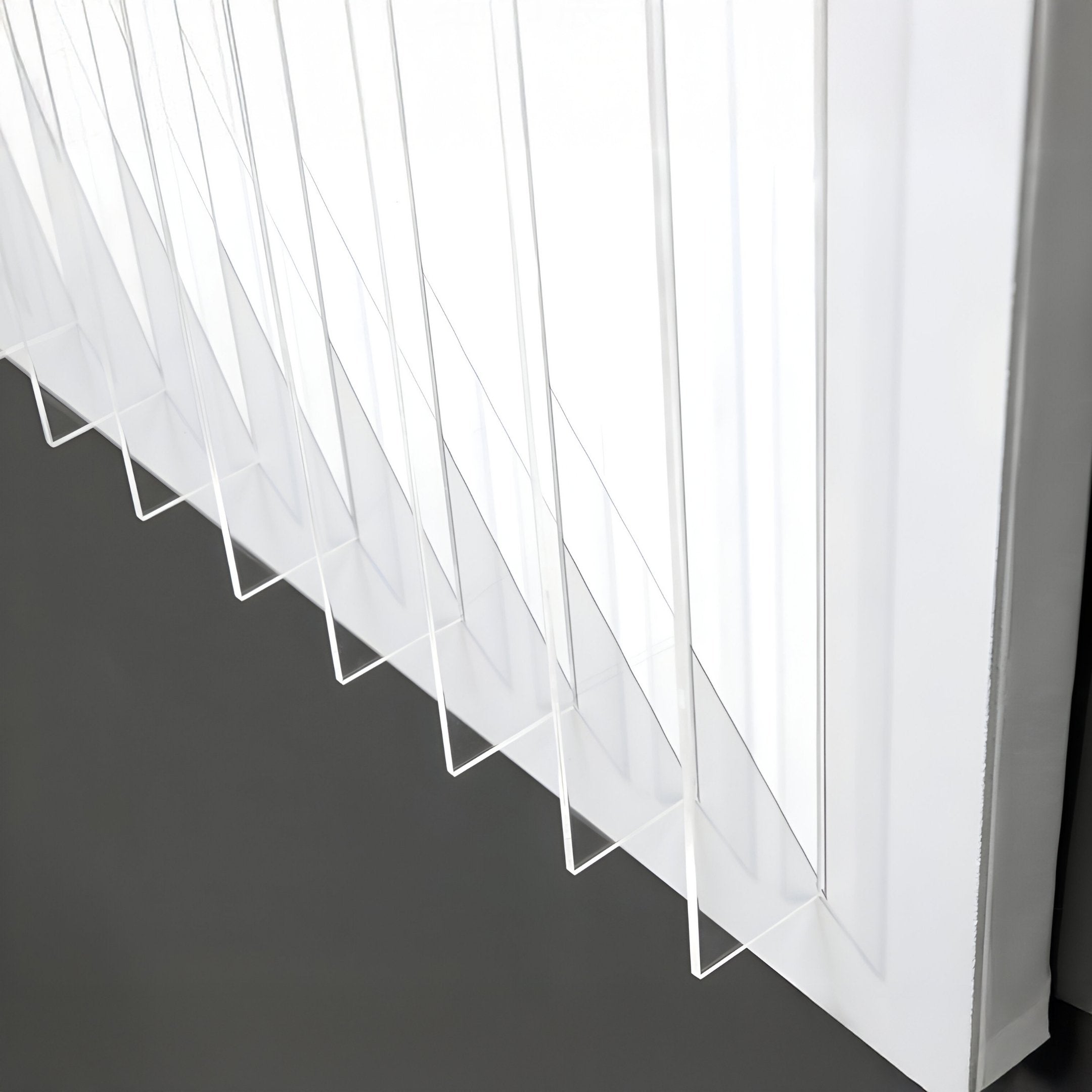 A close-up of a window with transparent vertical blinds, partially open, lets light filter through in geometric patterns—recalling the minimalist style of Giant Sculptures Verta Sky Blue Gradient Acrylic 3D Wall Art below.