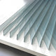 The Verta Blue Gradient Acrylic 3D Wall Art by Giant Sculptures features upright sheets in parallel rows, casting striking angular shadows and reflections reminiscent of sculptural artistry.