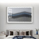 A modern bedroom features a grey upholstered bed, beige and brown accent pillows, a draped blanket, and the Tessera Silver Mist & Pastel Blue Line Acrylic 3D Wall Art by Giant Sculptures with metallic wavy blue accents above the headboard.