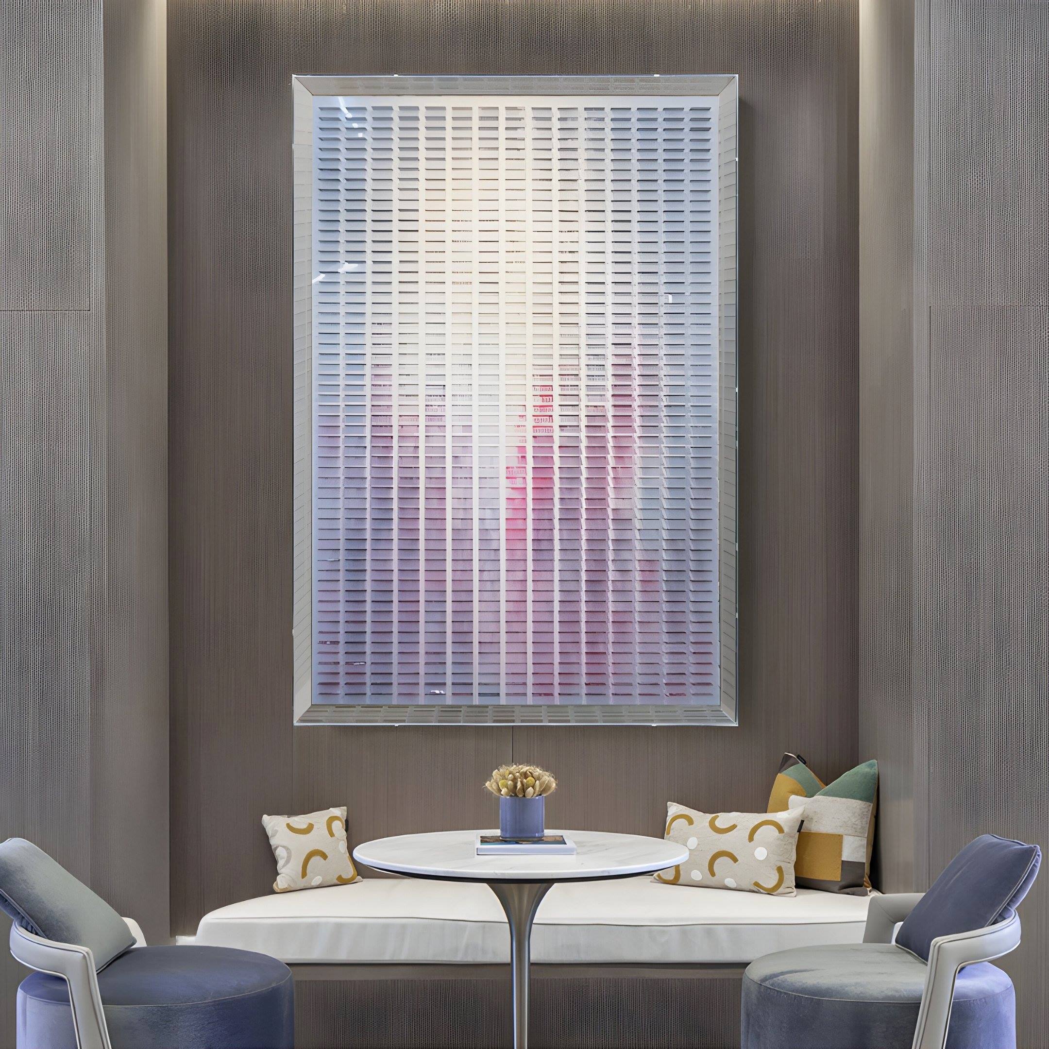 A modern lounge area with a round white table, two gray chairs, a built-in bench with patterned pillows, and the Chromat Orchid Blush Fade Acrylic 3D Wall Art by Giant Sculptures as striking contemporary decor above.