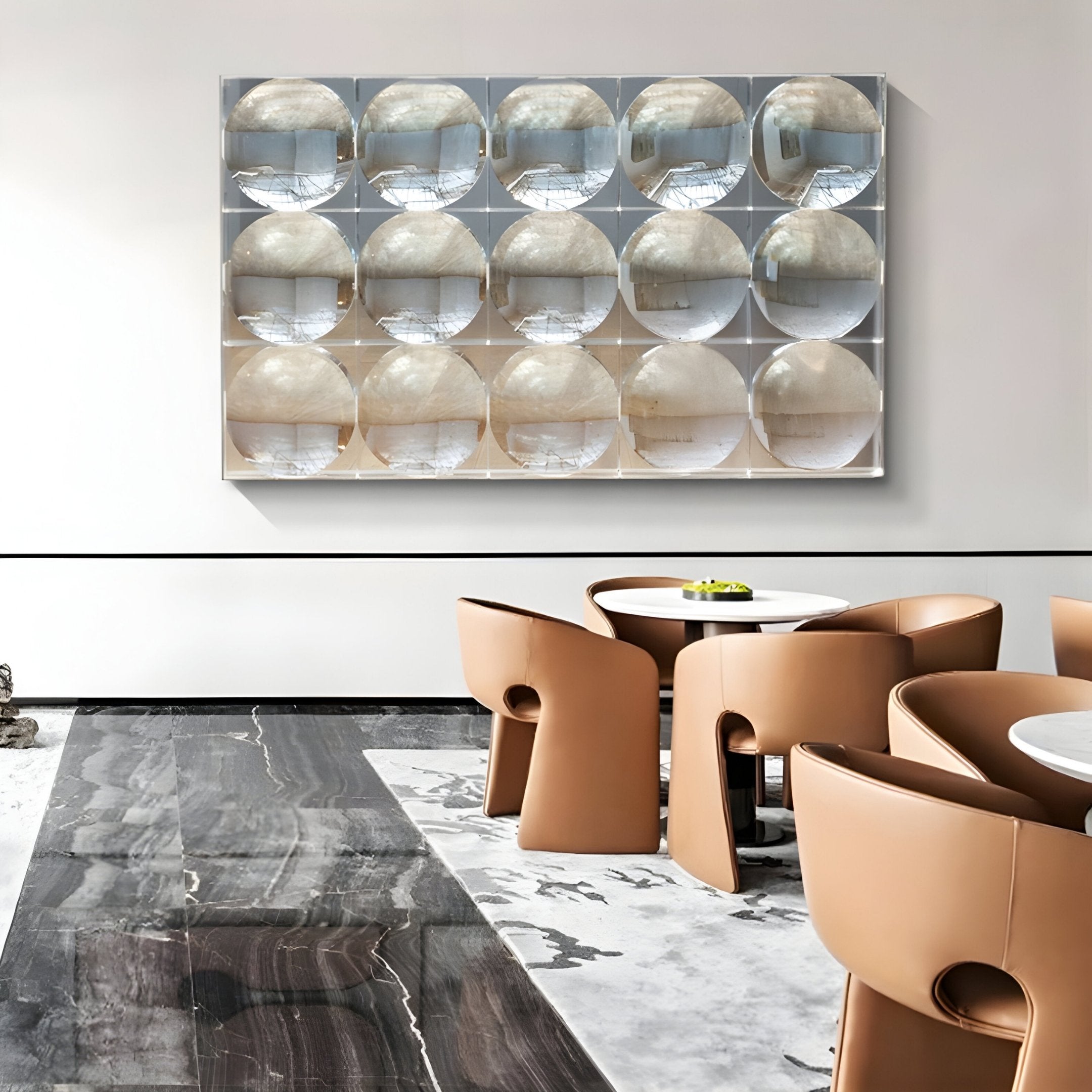 A modern interior with tan leather chairs, round white tables, black and white marble flooring, and a grid of Giant Sculptures’ Reflect Champagne Beige & Soft Silver Mirror Acrylic 3D Wall Art as striking contemporary wall decor.