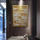 The Dynasty Dark Gold Landscape Framed Acrylic 3D Wall Art by Giant Sculptures hangs on a wood-paneled wall in a modern hallway with patterned floors and a nearby sculptural decor piece, showcasing intricate white architectural designs.