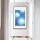 A modern hallway with white walls features a large abstract artwork in blue and white, accented by Glaciera Turquoise Sky Silver Acrylic 3D Wall Art from Giant Sculptures. A golden trim highlights the tiled floor along the walls base.