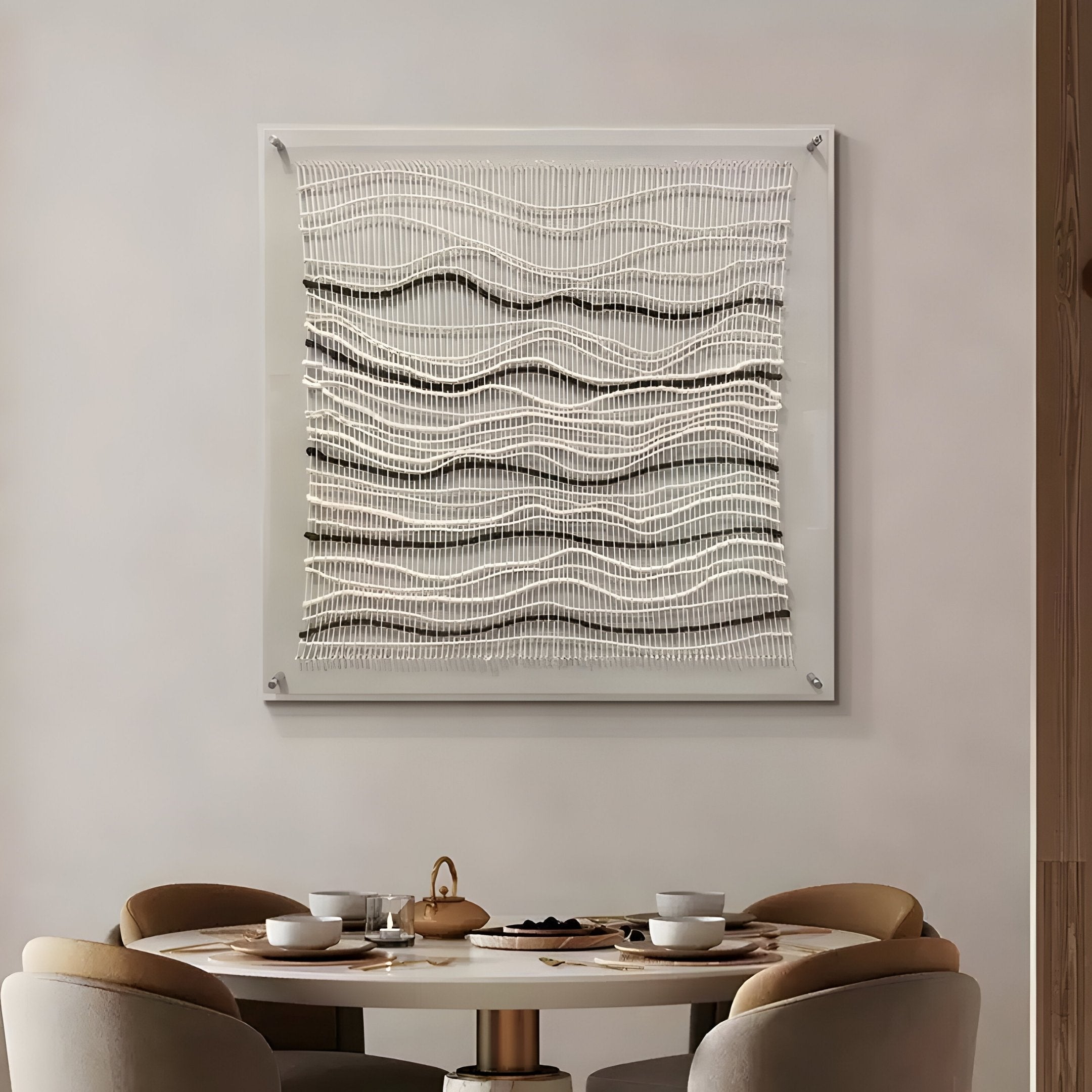 A round dining table set for four with dishes and a teapot sits beneath the Tanglewave Ivory & Charcoal Ripple Texture Acrylic 3D Wall Art by Giant Sculptures, adding striking contrast to the modern, neutral-toned dining area.