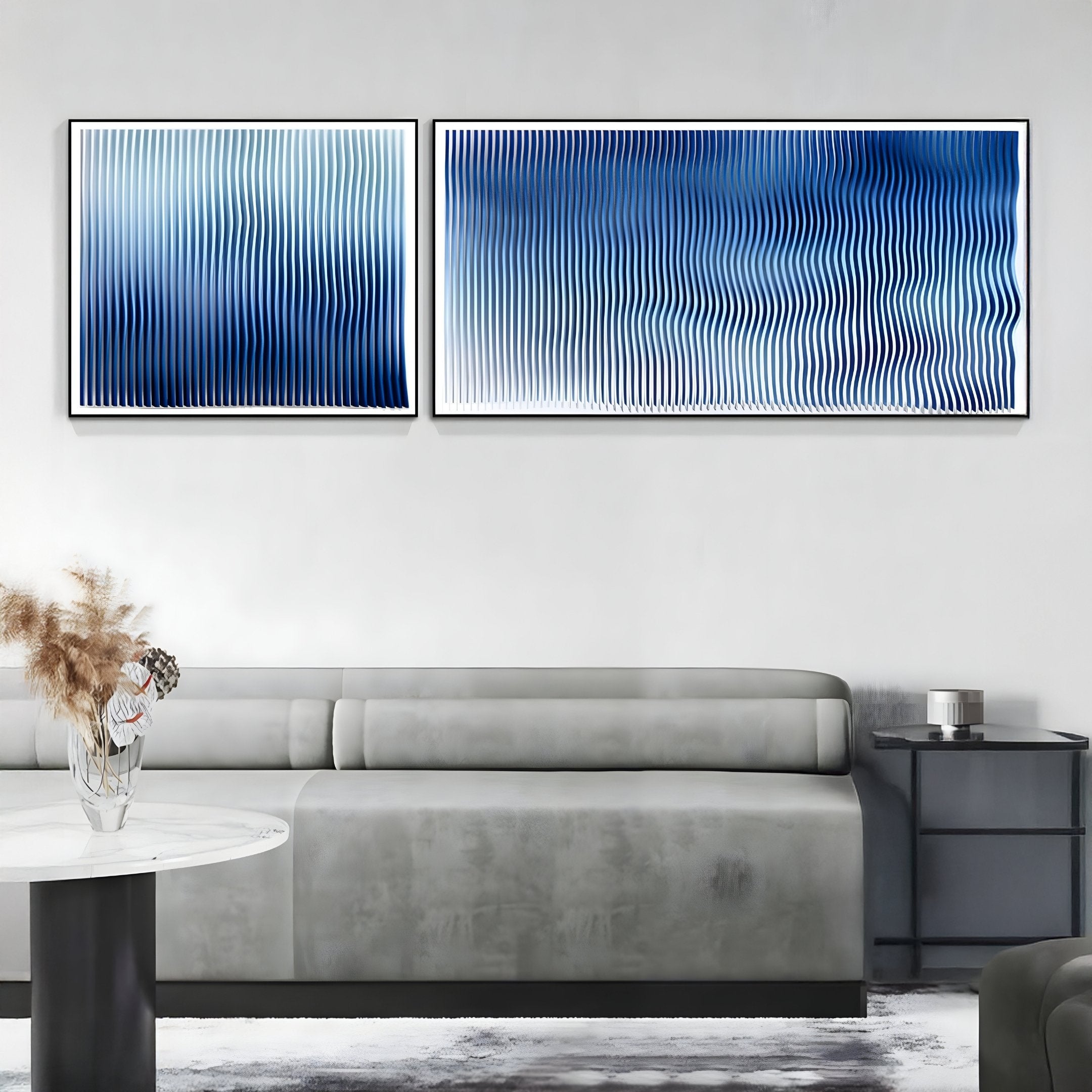 A modern living room with a light gray sofa, a round white table with dried flowers, and Giant Sculptures Current I Navy Sky & Icy White Acrylic 3D Wall Art as bold, abstract wave-patterned decor above the sofa.