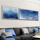 A modern living room features a black leather sofa, blue and patterned cushions, and Giant Sculptures’ Current I Navy Sky & Icy White Acrylic 3D Wall Art with wavy lines that add depth to the light wall.