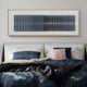 A modern bedroom features a bed with blue and gray bedding, two pillows—one pink and one gray—and the Flowline Slate Blue Gradient Acrylic 3D Wall Art by Giant Sculptures with vertical black and white lines above the headboard.
