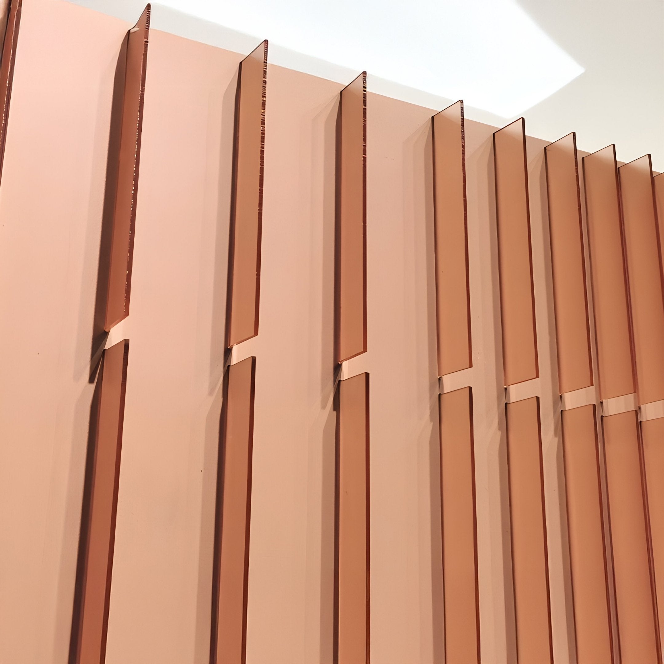 Close-up of Flowline Copper Blush Gradient Acrylic 3D Wall Art by Giant Sculptures, showing vertical, evenly spaced peach-toned panels with narrow gaps that create a modern geometric pattern under bright lighting.