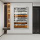 A modern hallway showcases the Giant Sculptures Rhythm Tangerine & Silver Layered Stripe Leather 3D Wall Art, featuring bold horizontal stripes. Decorative shelves sit left, a dark door right, creating a well-lit, minimalistic space.