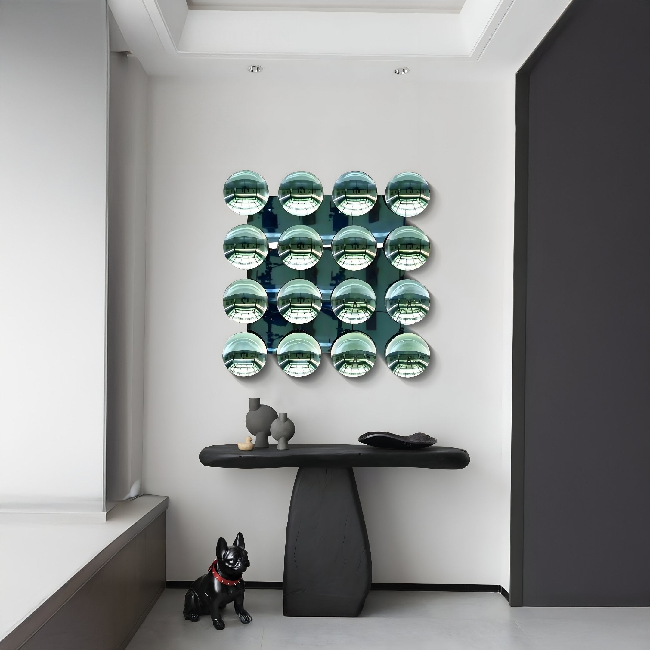 A modern entryway features a black sculptural console, decorative objects, a black dog statue, and striking Dome Emerald Green Acrylic 3D Wall Art by Giant Sculptures—16 reflective spheres arranged in a grid for a contemporary touch.