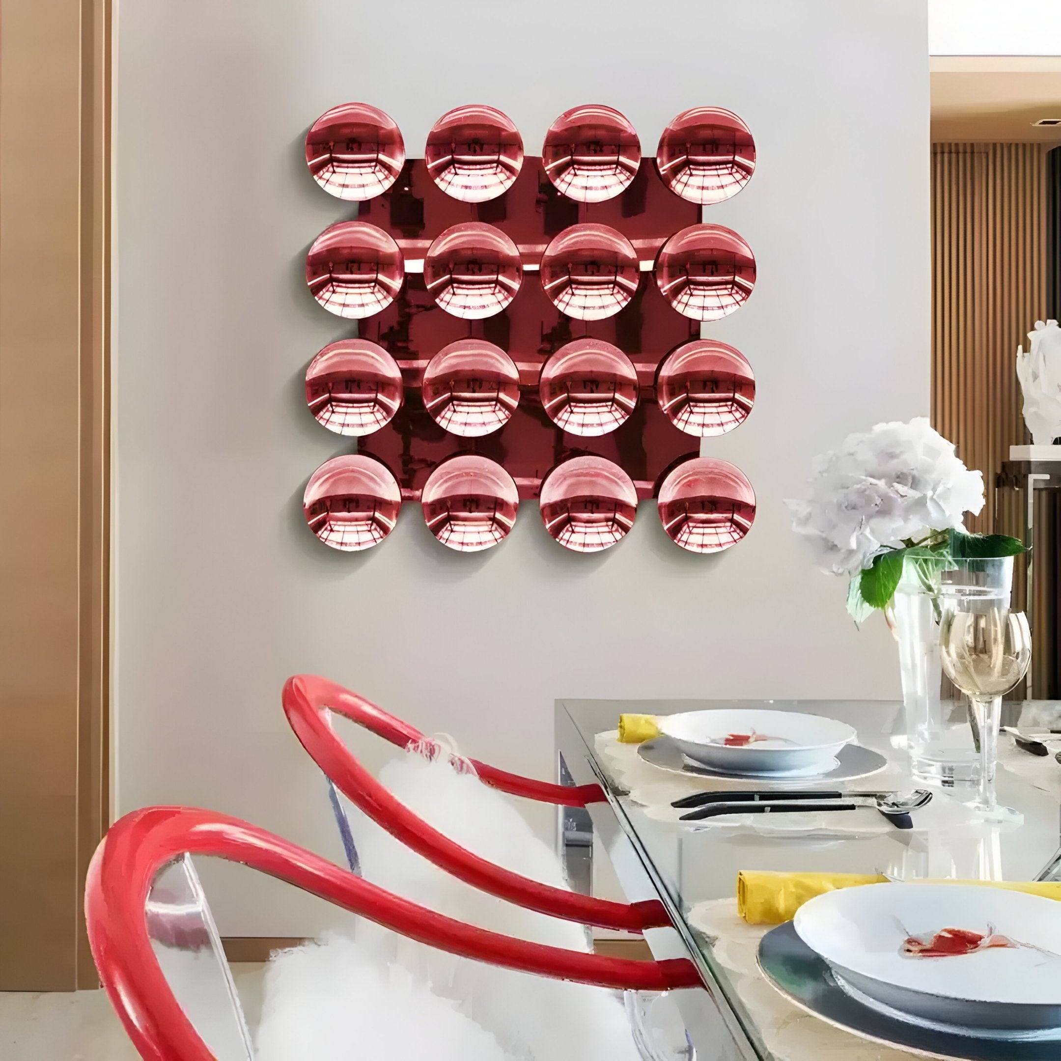 A modern dining room features a glass table with clear chairs accented in red, highlighted by the Dome Crimson Red Acrylic 3D Wall Art from Giant Sculptures—a bold grid of 16 shiny red spheres creating a striking modern statement.