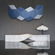 A modern interior showcases Giant Sculptures’ Vertex Deep Navy & White Ridge Acrylic & Wood Carving 3D Wall Art, paired with a white sculptural bench and a cloud-shaped lamp, all set against a dark gray wall and glossy floor.