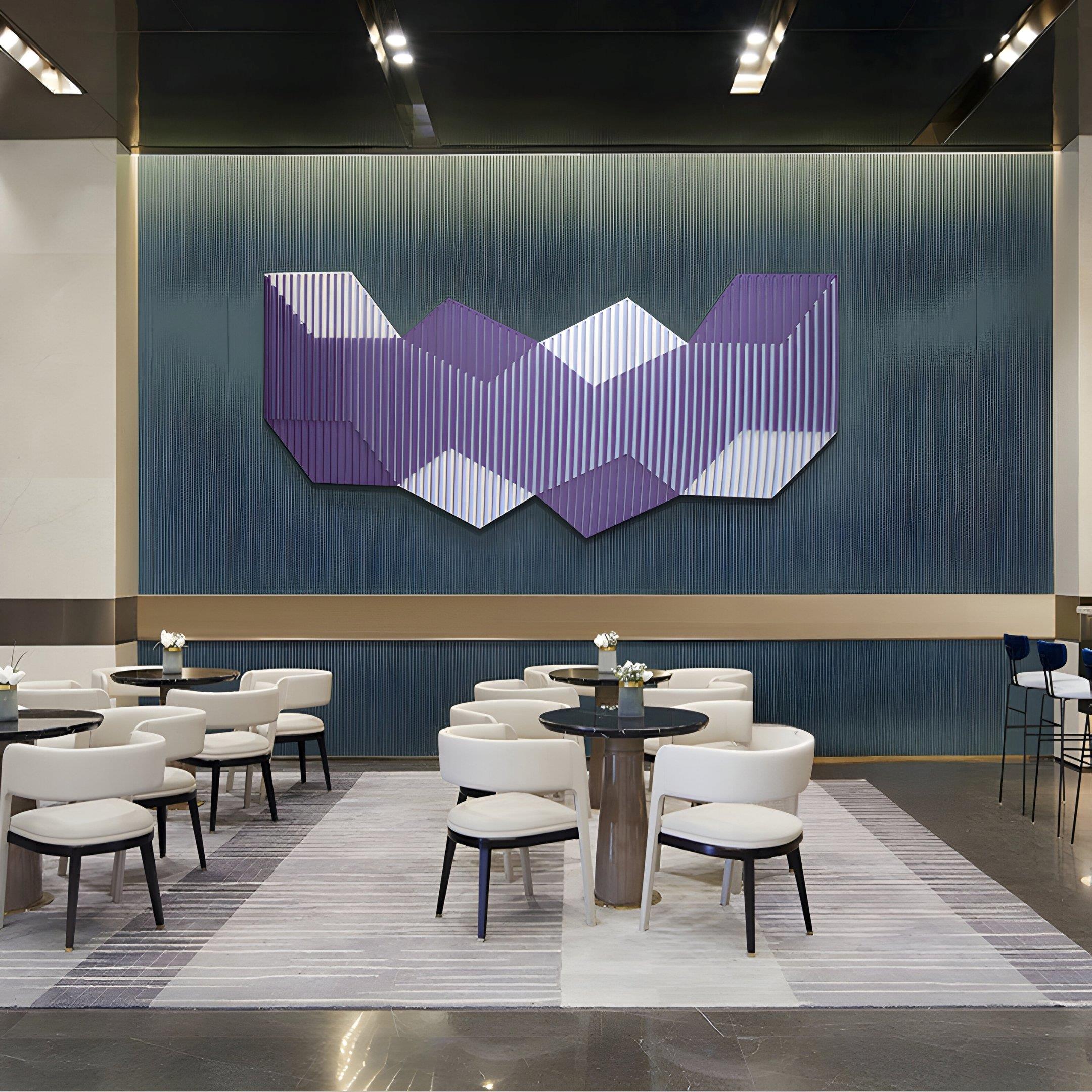 A modern lounge with white chairs and round tables on a striped rug features the Vertex Lavender & Soft Lilac Ridge Acrylic & Wood Carving 3D Wall Art by Giant Sculptures and a blue gradient accent wall in the background.
