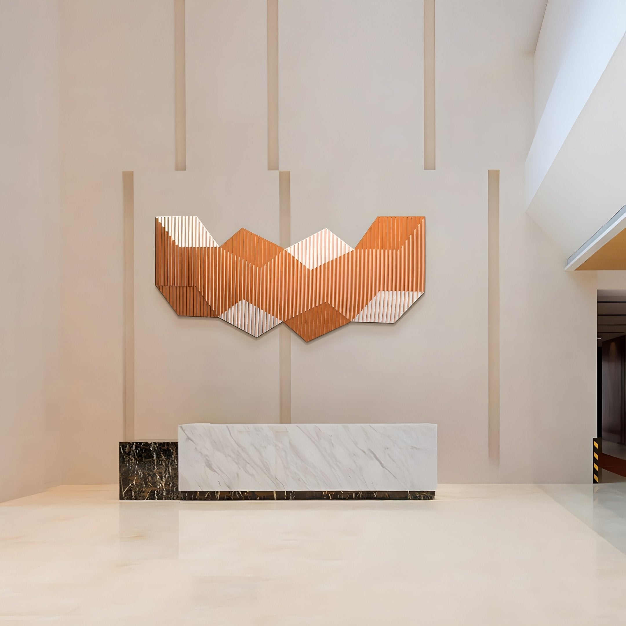 A minimalist lobby features a white marble reception desk and Giant Sculptures Vertex Orange & Cream Ridge Acrylic & Wood Carving 3D Wall Art, adding warm tones and depth against a light wall with vertical accents.