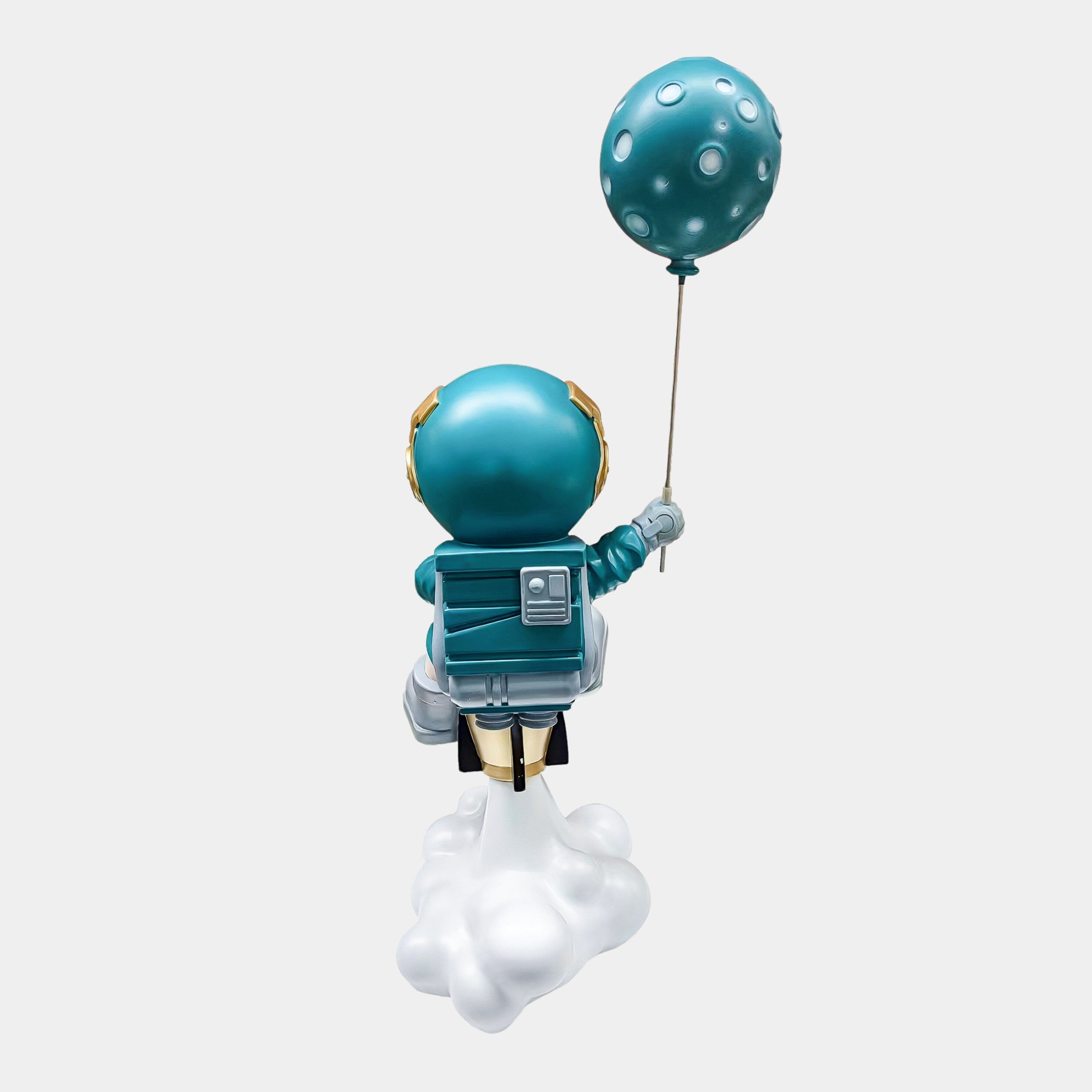 The Giant Sculptures Galactic Blue Astronaut Rocket Lift-Off Balloon Sculpture (95cm) features a stylized astronaut in a teal suit with gold accents floating on a cloud, holding a teal moon balloon against a light background.