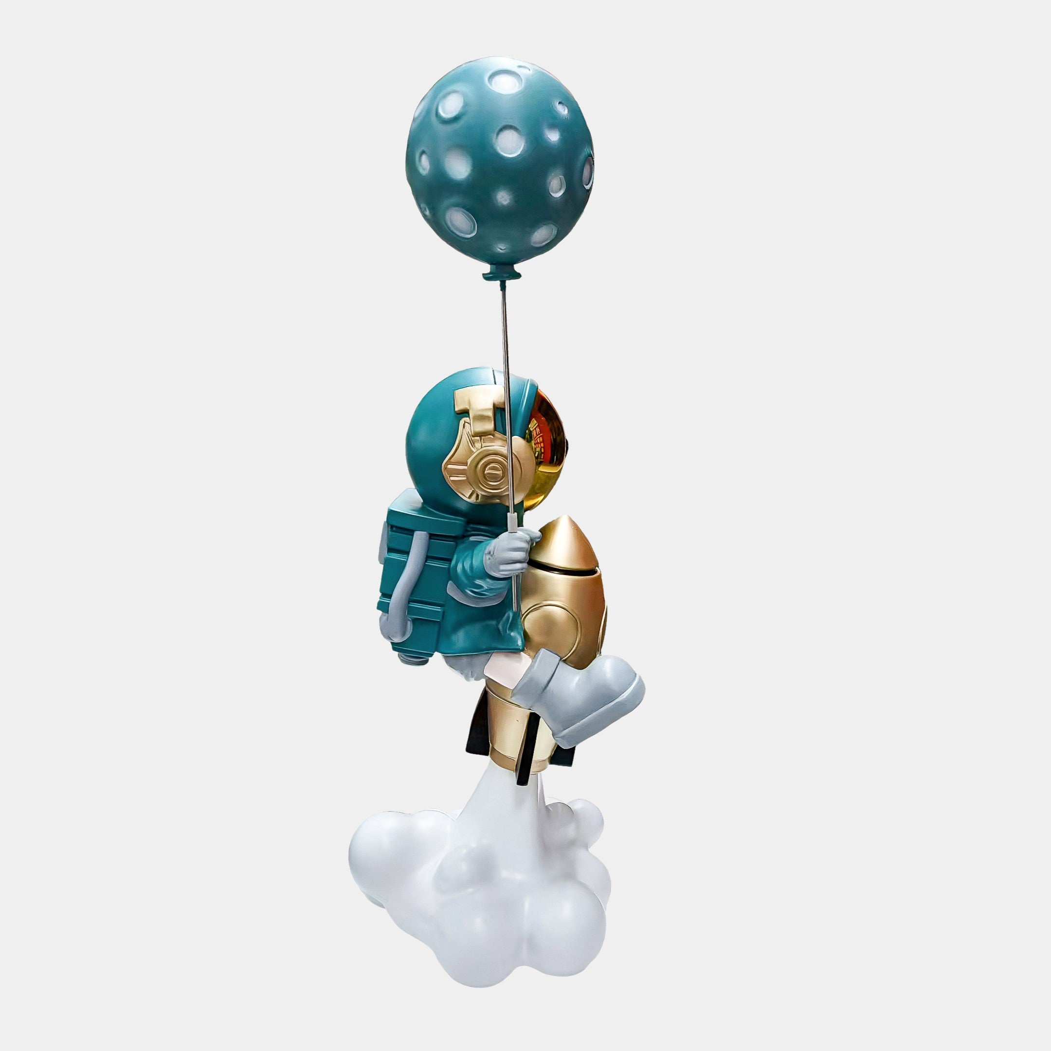 The Giant Sculptures Galactic Blue Astronaut Rocket Lift-Off Balloon Sculpture (95cm) features a teal-suited astronaut with a gold helmet holding a moon balloon, standing on cloud-like shapes—an enchanting decor for space enthusiasts.