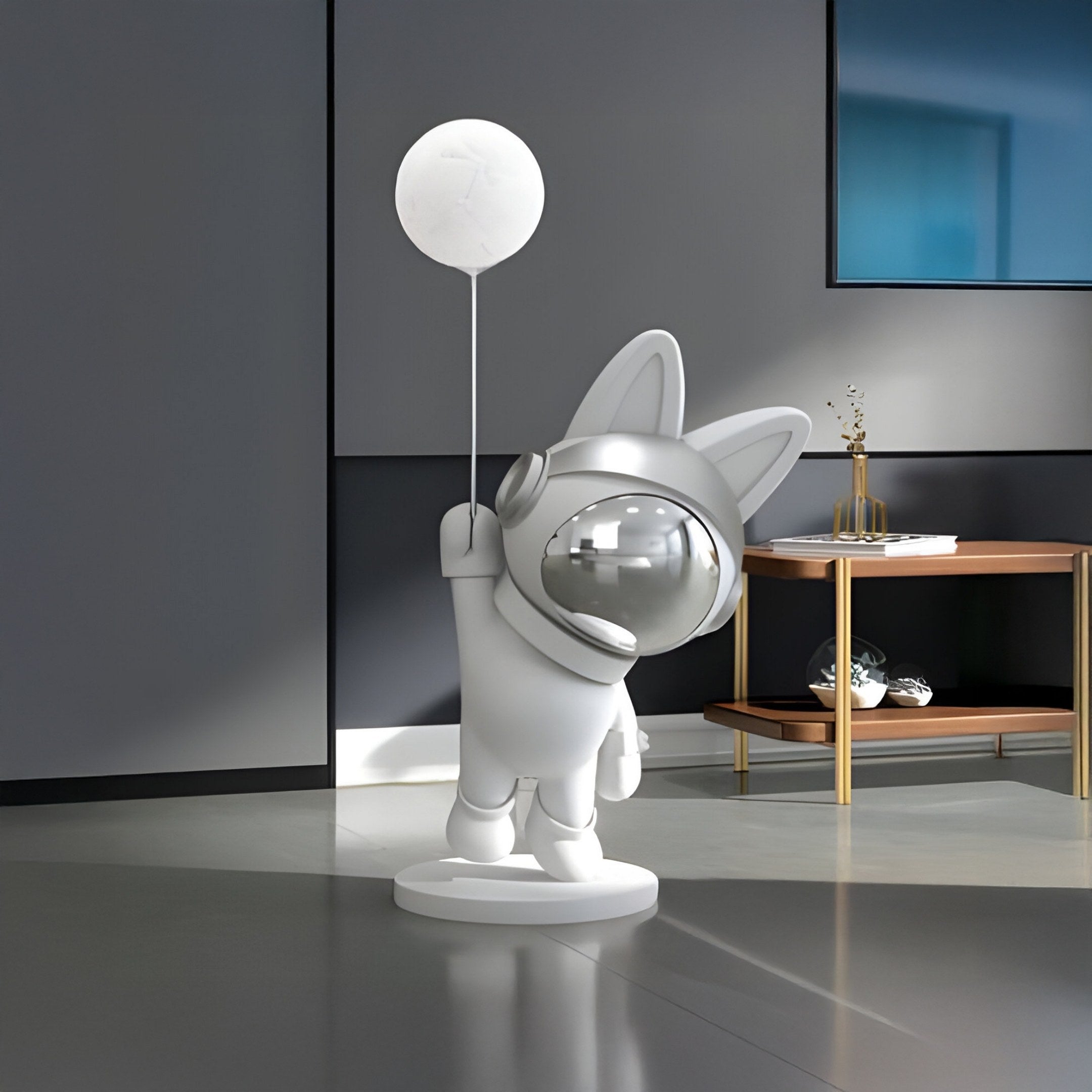 A whimsical Cosmic Chrome Astronaut Bunny Glow Balloon Sculpture by Giant Sculptures adds charm to a modern minimalist room, where it holds a balloon near a console table covered with decor items and beneath an abstract painting.