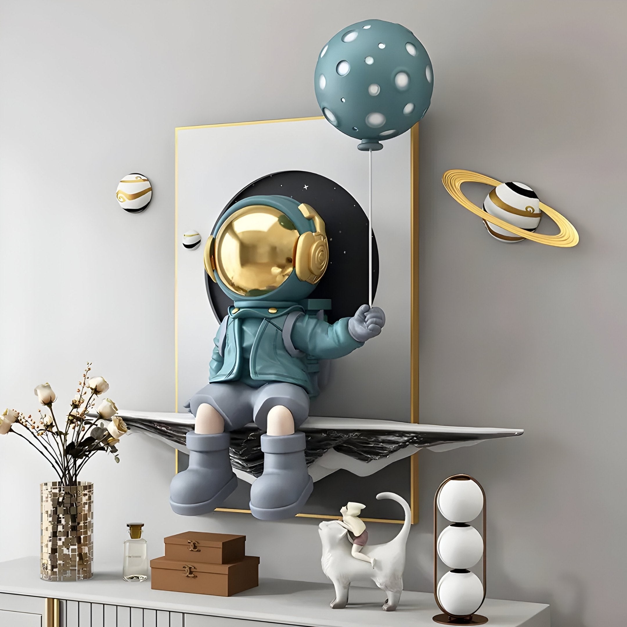 A decorative scene showcasing Giant Sculptures Blue Balloon Astronaut 3D Portal Wall Art on a floating shelf, with planets and stars from Cosmic Décor on the wall. A small white cat and decorative items adorn the table below, creating an enchanting celestial setup.