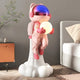 The Giant Sculptures Stellar Pink Astronaut Glow Lift-Off Sculpture (110cm) features a shiny-helmeted astronaut on a white cloud base holding a glowing orb, perfect for adding charm to modern bedrooms and contemporary interiors.