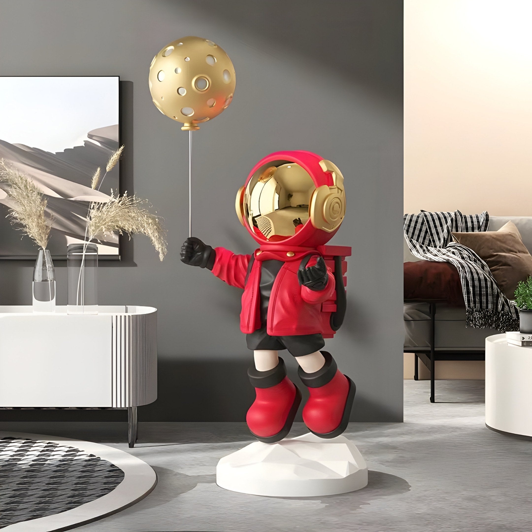 A Solar Red Astronaut Moon Balloon Sculpture by Giant Sculptures, standing 110cm tall, adorns a modern room with a circular rug, white table, and neutral-colored furniture for a contemporary look.