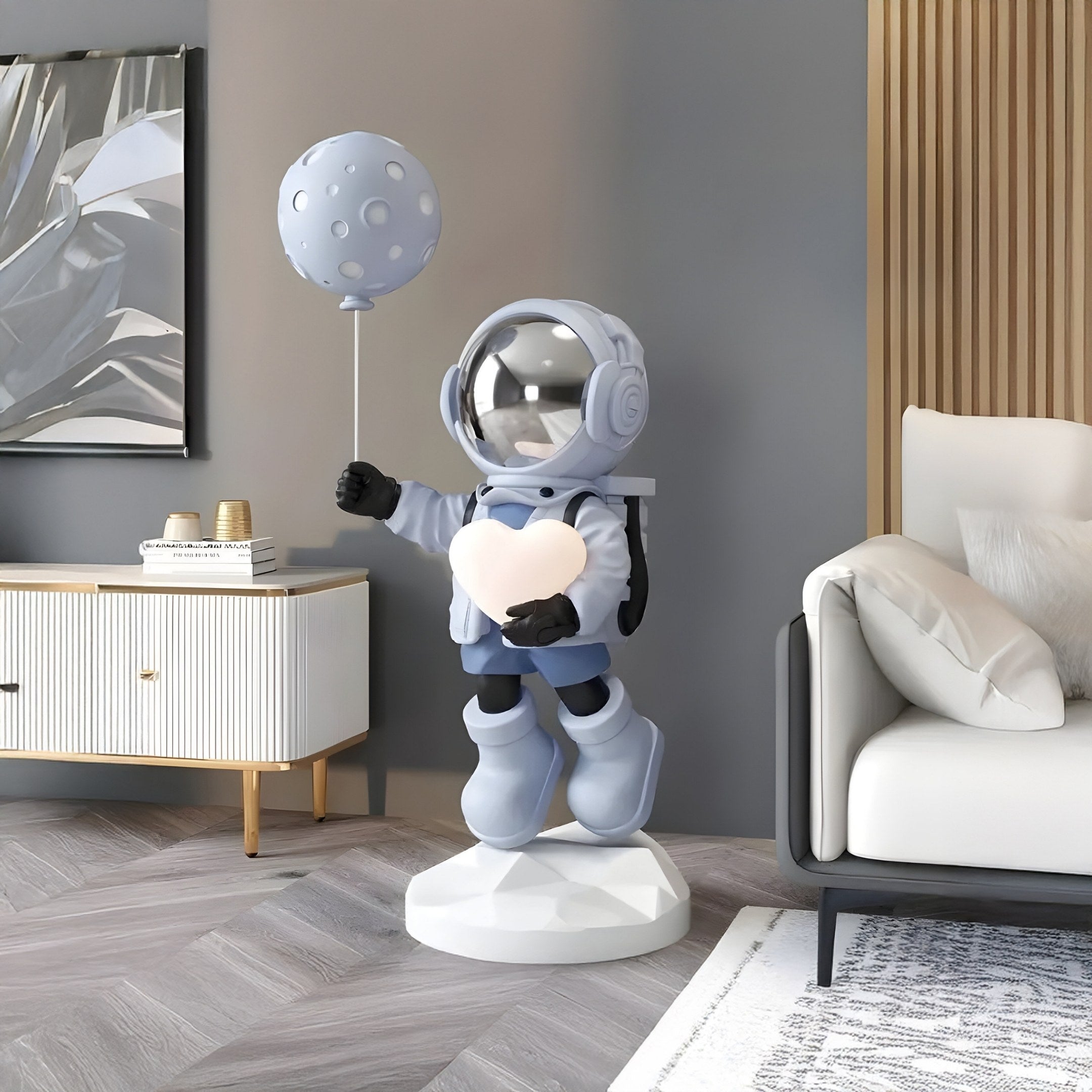 The modern living room, featuring a white couch, wooden sideboard, and abstract art, is subtly enhanced by the Cosmic Sky Astronaut Glow Heart Balloon Sculpture - 110cm from Giant Sculptures. This celestial centerpiece adds charm with its moon-shaped balloon against a neutral color palette.