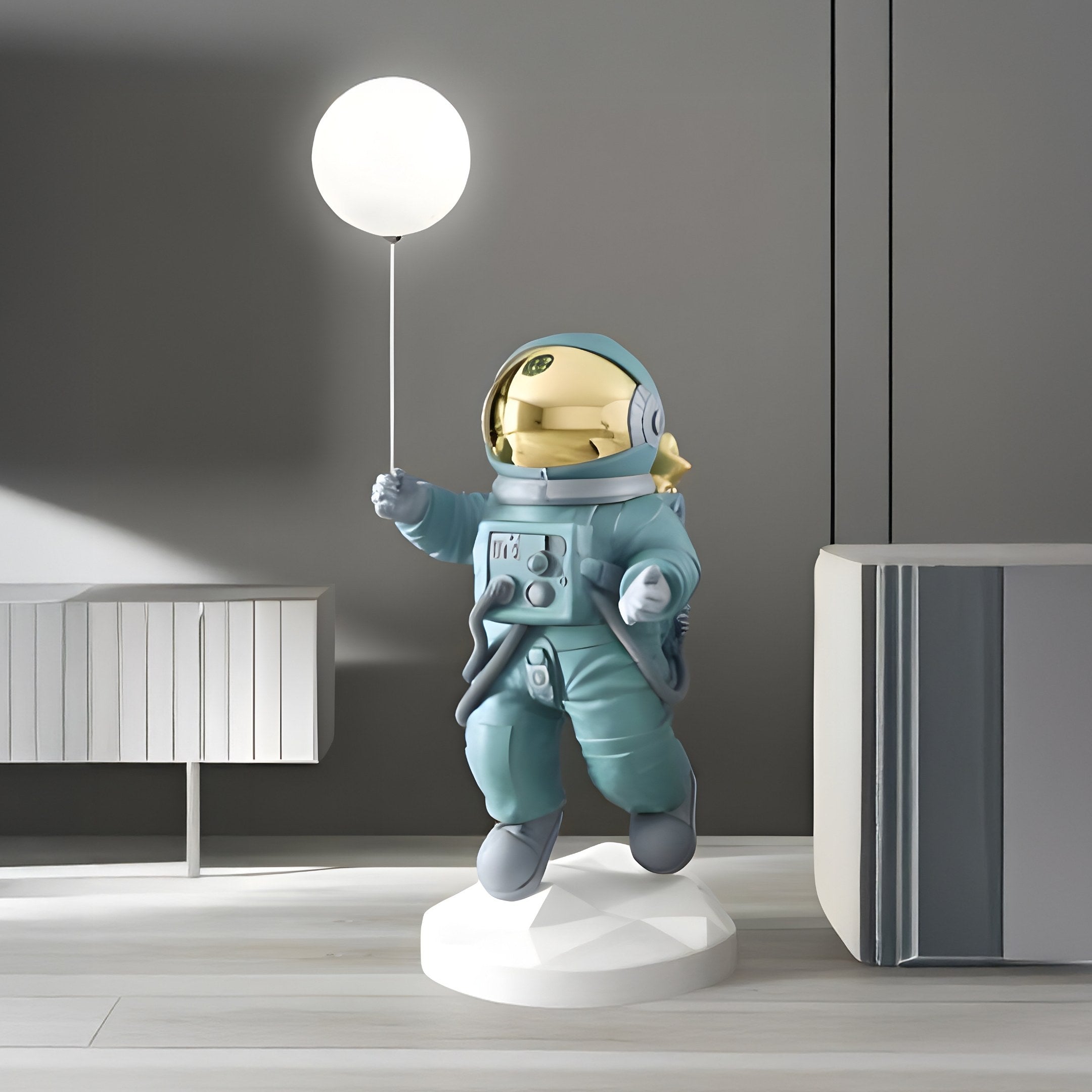 A Galactic Blue Astronaut Ranger Glow Balloon Sculpture by Giant Sculptures stands on a round platform in a modern room, with sleek gray tones and minimalist furniture, creating enchanting space-themed décor.