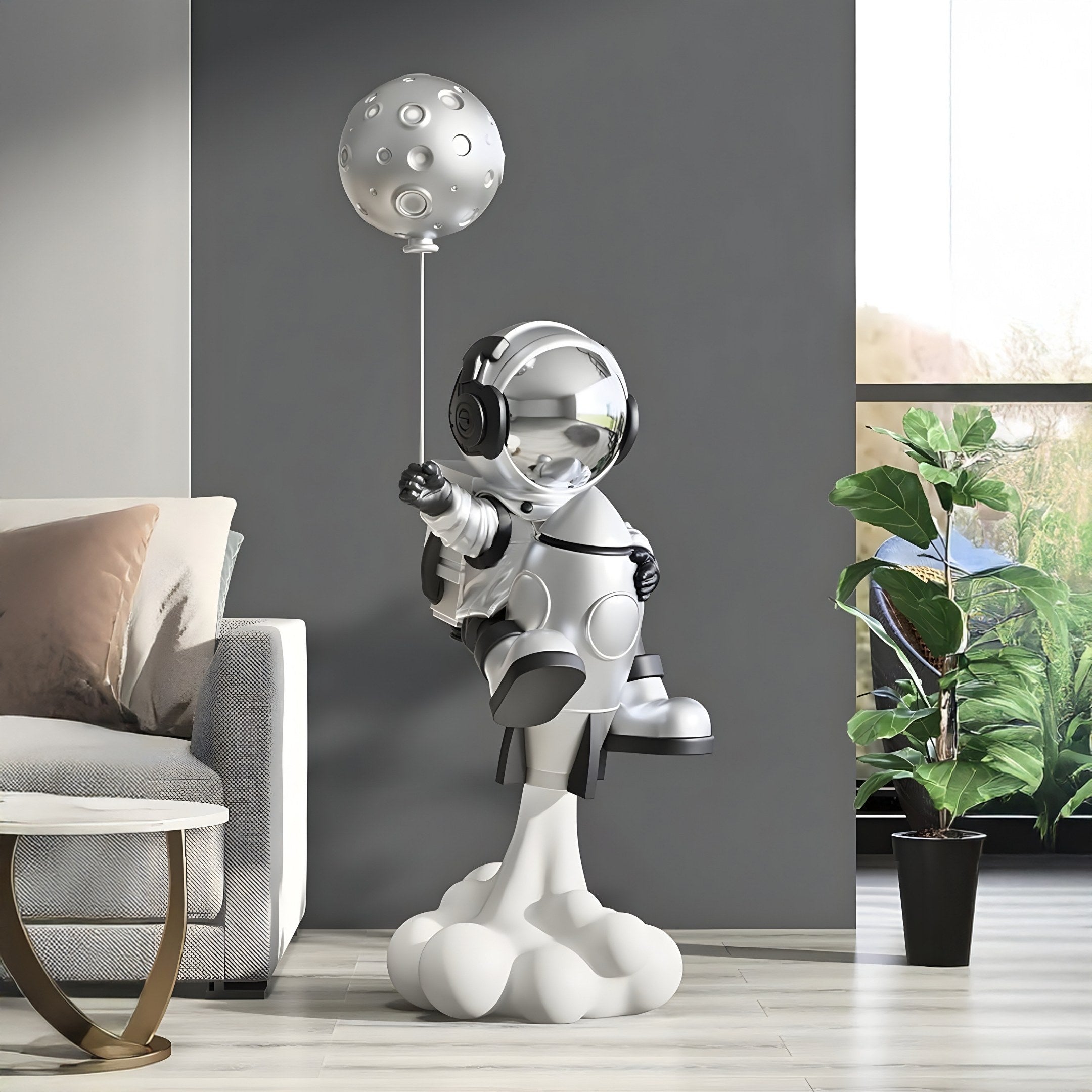 A metallic Lunar Silver Astronaut Rocket Lift-Off Balloon Sculpture from Giant Sculptures stands on a cloud base beside a modern couch and tall green potted plant. Its reflective surface shines against the dark wall, enhancing its space-inspired aura.