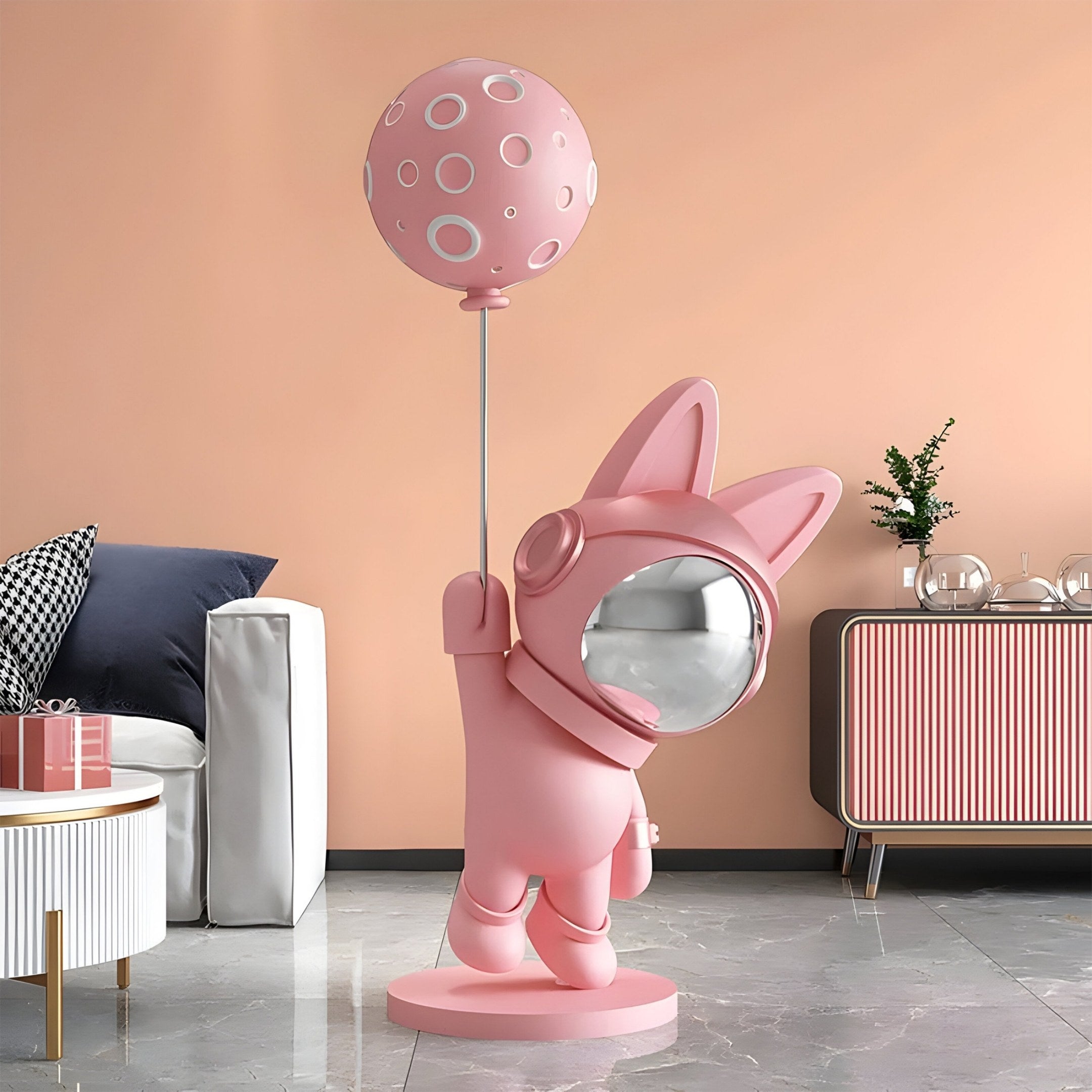 The 150cm Candy Pink Astronaut Bunny Moon Balloon Sculpture by Giant Sculptures features long-eared bunny holding a moon balloon on a pole. It has a shiny, metallic face and stands on a circular base against a soft pink wall with a modern console and small plant for whimsical space-themed decor.