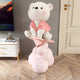 Blush Pink Cloudsit Glider Bear Sculpture by Giant Sculptures, a 150cm resin bear in ivory and soft pink seated on a paper glider atop layered pink cloud forms, shown in a living room beside a white cabinet.