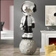 Lunar Silver Astronaut Beats On Moon Sculpture by Giant Sculptures, 210cm resin figure in silver jacket and black suit with reflective visor and headphones, standing on a cratered moon base, displayed beside a fireplace in a modern living room.