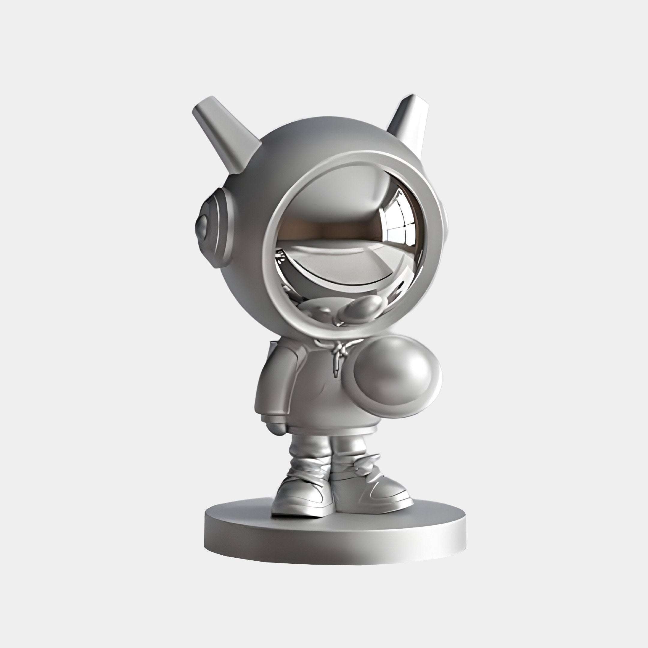 The Giant Sculptures Cosmic Chrome Astronaut DJ Figure features a 3D-rendered metallic astronaut with a round helmet, reflective visor, antennae, headphones, and a smile, standing on a circular base in a hoodie and sneakers. Its shiny 30cm surface emits futuristic energy.