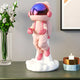 The Giant Sculptures Stellar Pink Astronaut Lift-Off Mini Figure (30cm) features a resin astronaut with a shiny visor floating above a white cloud, perfect for tabletops alongside decor like vases, candles, and photos.