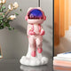 The Stellar Pink Astronaut Lift-Off Mini Figure by Giant Sculptures stands 30cm tall, featuring cat-like ears and a shiny purple visor atop a white cloud, adding a whimsical touch to any tabletop or modern decor.