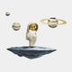 The White & Gold Orbit Odyssey Star Astronaut 3D Wall Art by Giant Sculptures features a small astronaut with a reflective gold helmet holding a star on a floating rock, surrounded by three spherical objects with black and gold patterns, including one with Saturn-like rings.